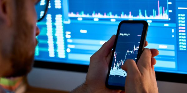 Trader analizuje wykresy na telefonie i komputerze, aby wykorzystać Pivoi Points